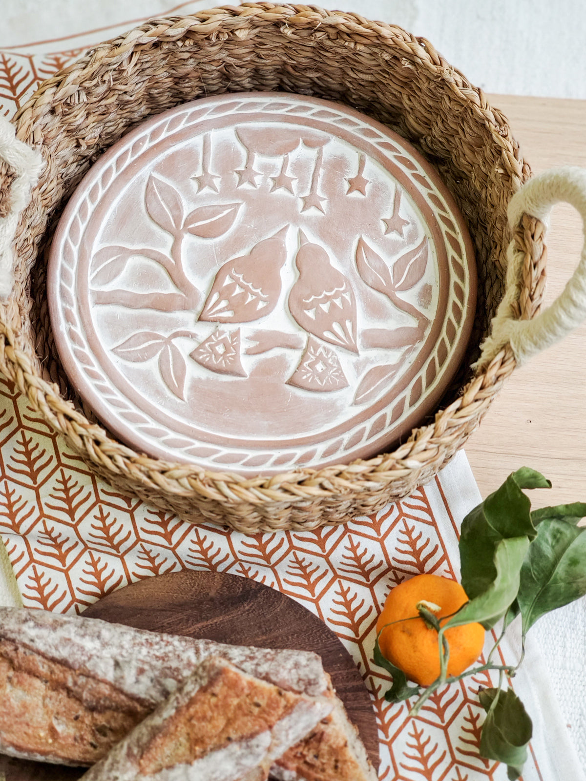Decorative ceramic plate with bird design in a woven basket on a patterned surface.