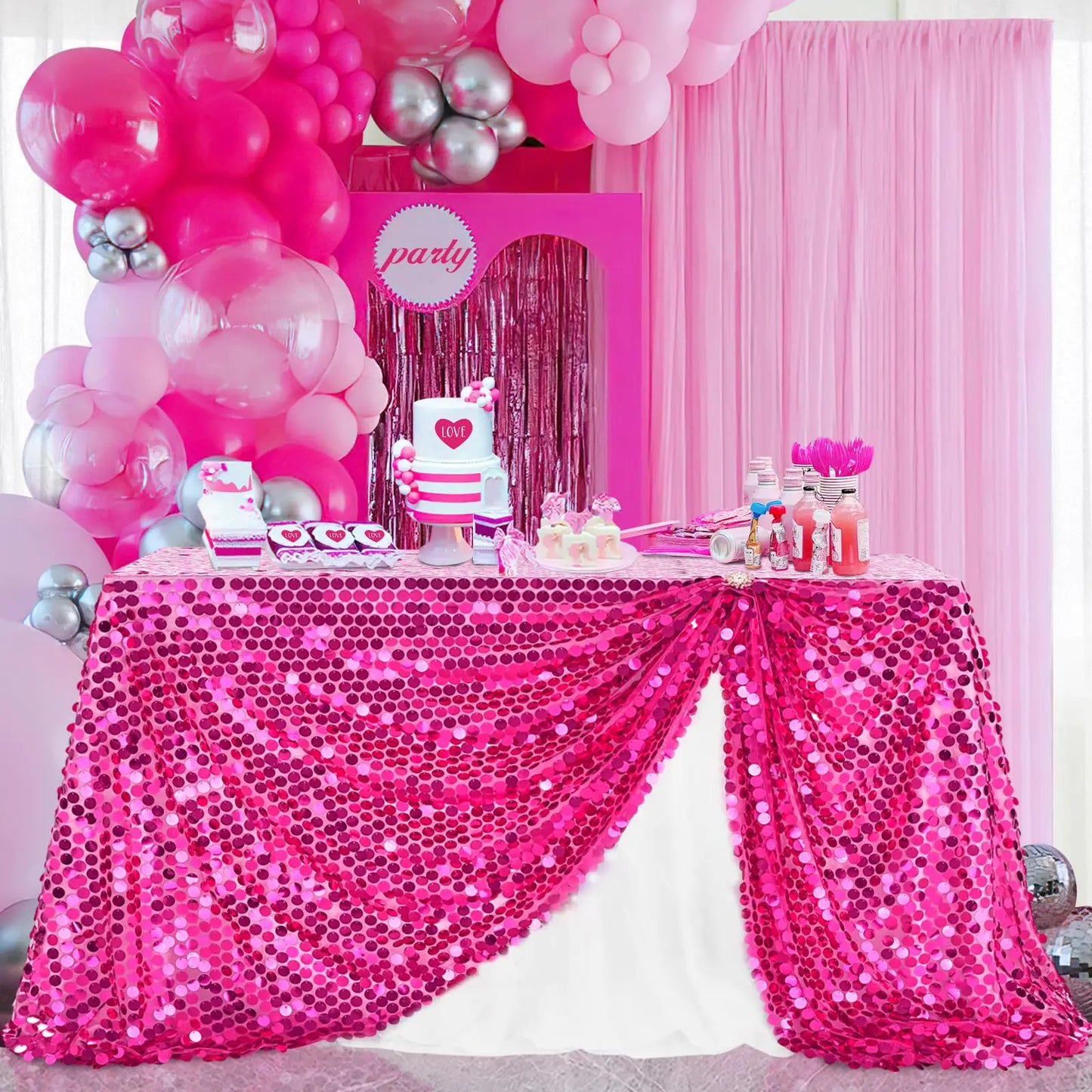Pink-themed party setup with balloons, cake, and sequin tablecloth.
